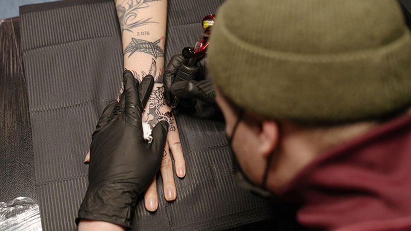 artist tattooing in the hand