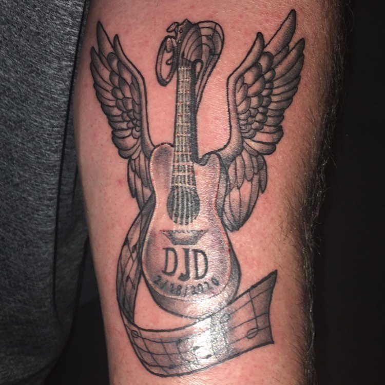 guitar with angel wings tattoo on leg
