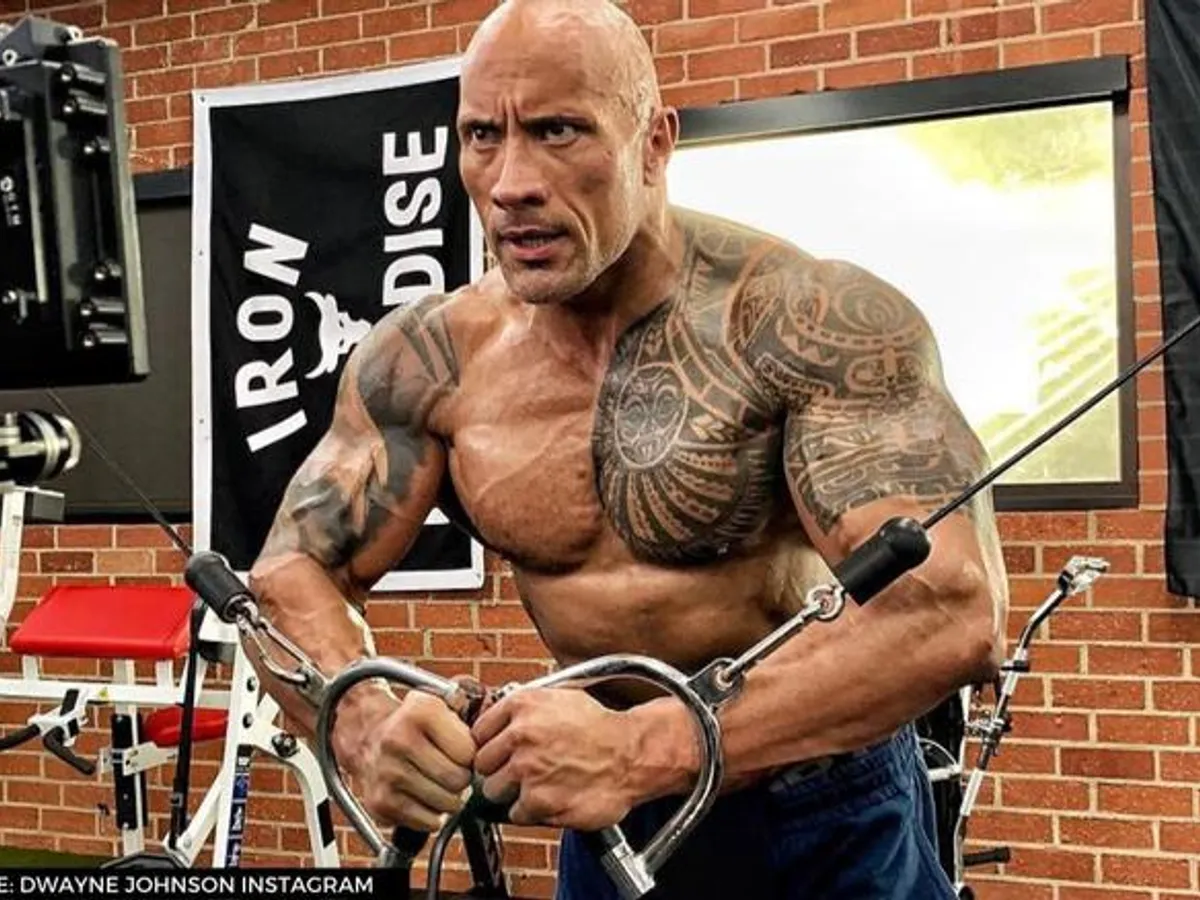 The Rock actor doing weights with tribal chest tattoo